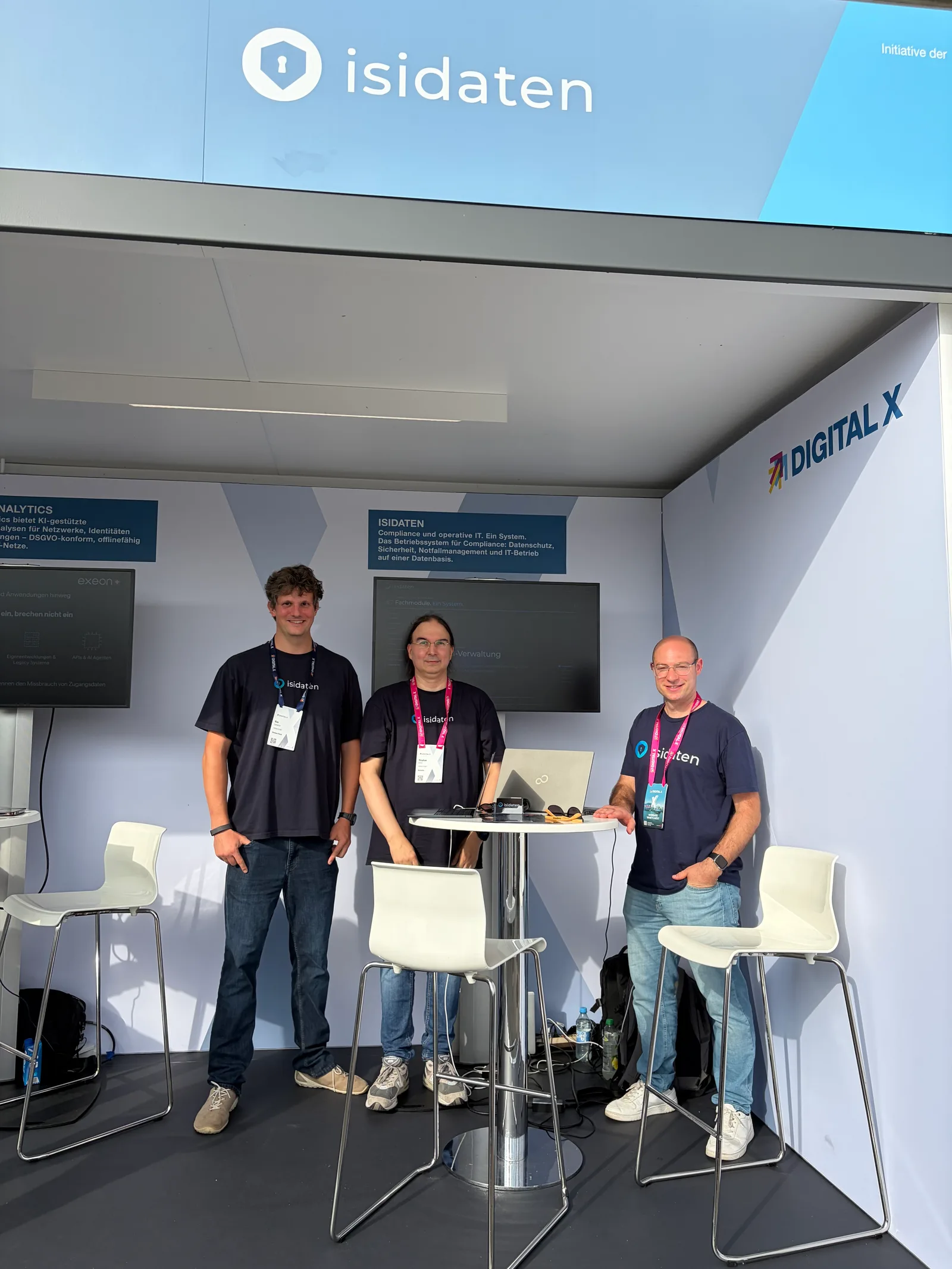 Die drei Gründer der isidaten GmbH an ihrem Stand, darüber der isidaten-Schriftzug.